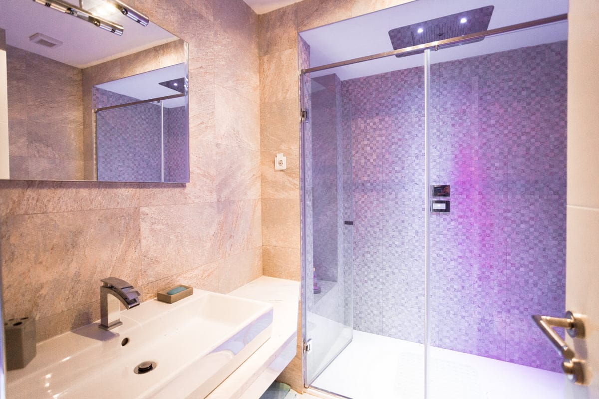 Salle de bains moderne avec cabine de douche et éclairage dans un appartement, Ljuta, Monténégro. Finition carrelée de qualité.