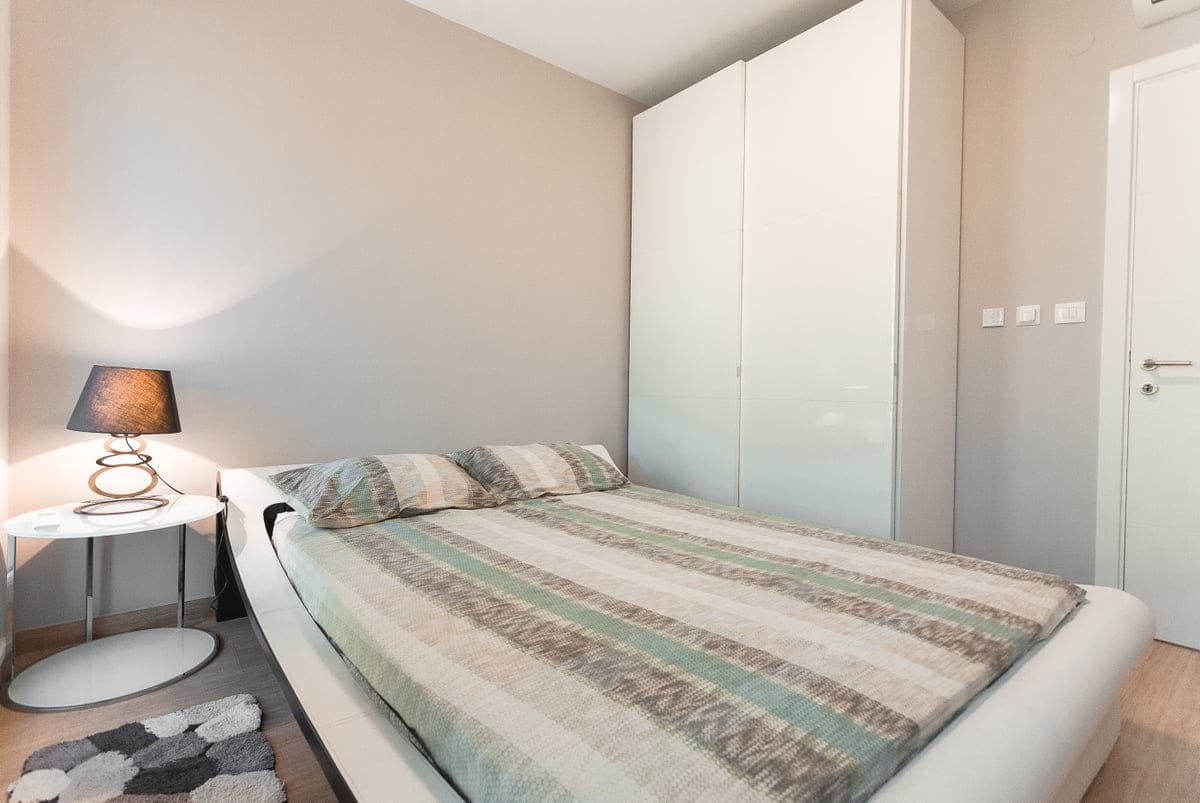 Chambre confortable avec un lit double et une armoire blanche dans un appartement, village de Ljuta, Monténégro. Intérieur moderne.