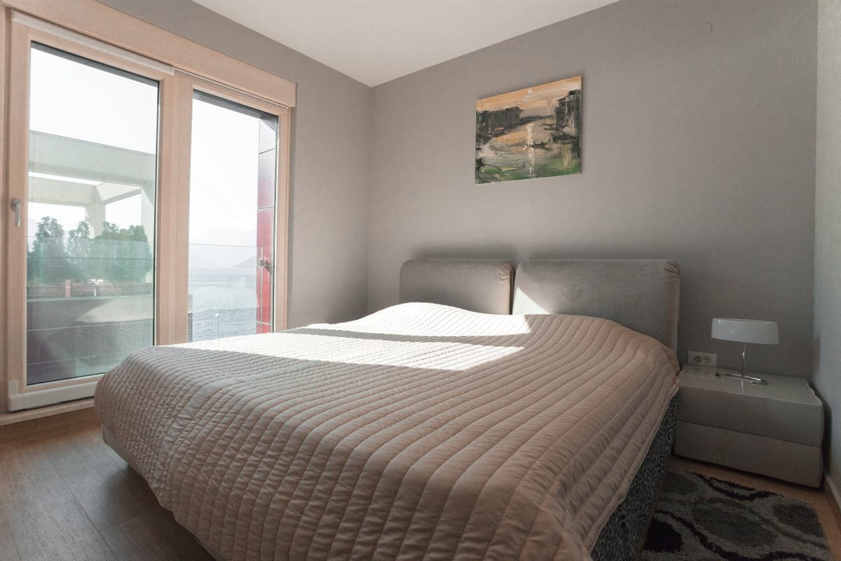 Chambre dans un appartement à Ljuta, Monténégro : lit double, fenêtre panoramique avec vue sur la mer et intérieur moderne.