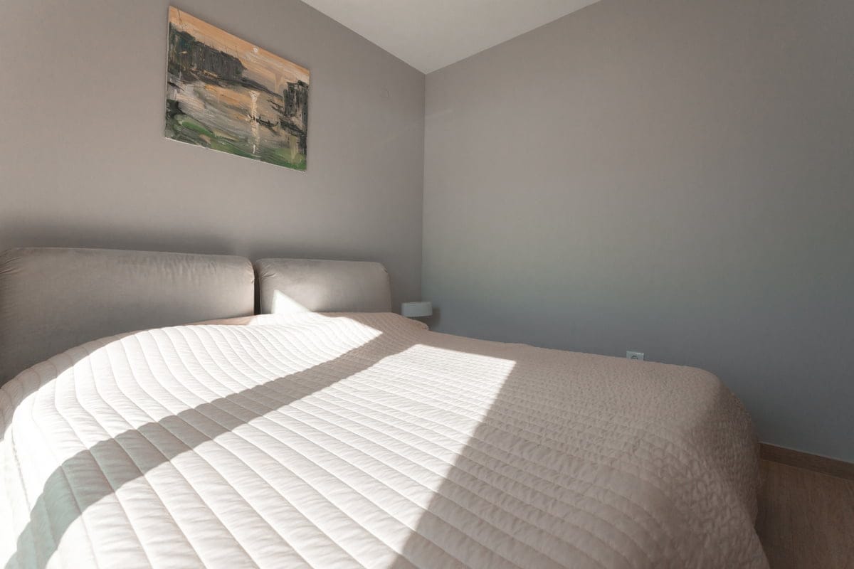 Chambre confortable avec lit double dans un appartement à Ljuta, Monténégro : intérieur moderne et tons clairs.