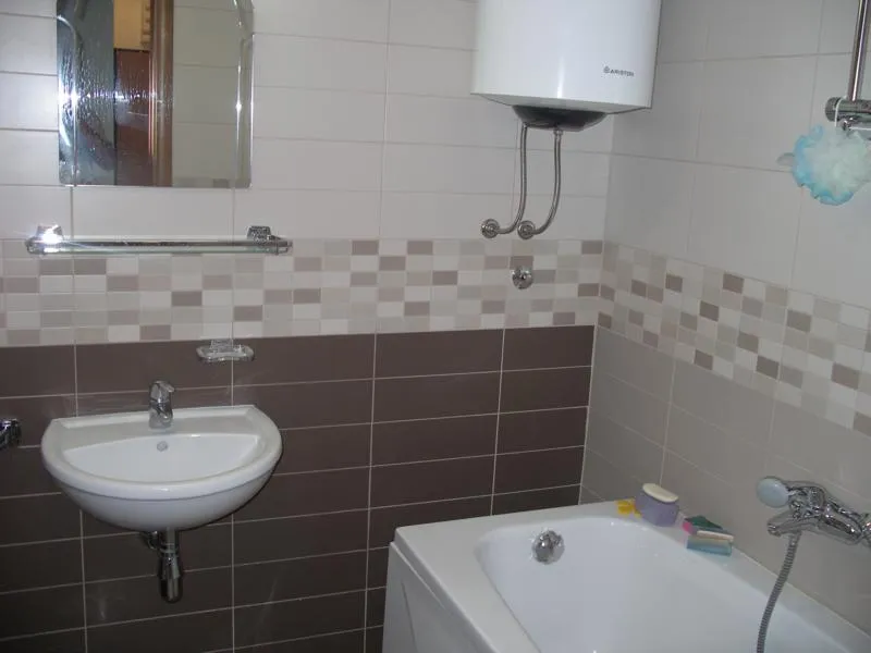Modernes Badezimmer mit Fliesen in einer Wohnung in Herceg Novi, Montenegro: Badewanne, Waschbecken und Boiler sind installiert.