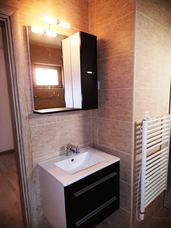 Modernes Badezimmer in einer Wohnung in Bečići, Montenegro: Waschtisch mit Waschbecken, beleuchteter Spiegel und Handtuchheizkörper.