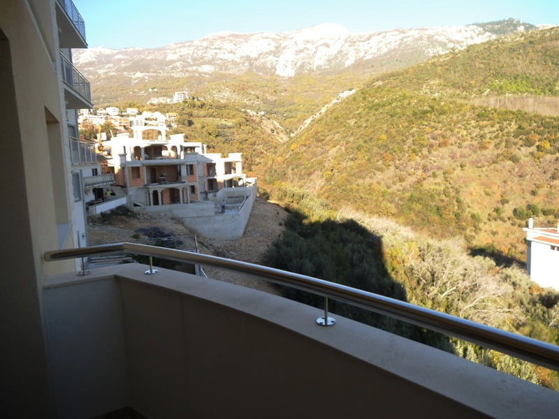 Blick vom Balkon einer Wohnung in Bečići, Montenegro: Panorama der Berge, hügelige Landschaft und benachbarte Wohngebäude im Bau.