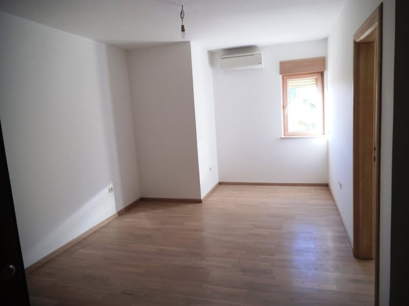 Helles Schlafzimmer mit Parkett und Klimaanlage in einer Wohnung, Stadt Bečići, Montenegro. Leerer Raum mit Fenster.