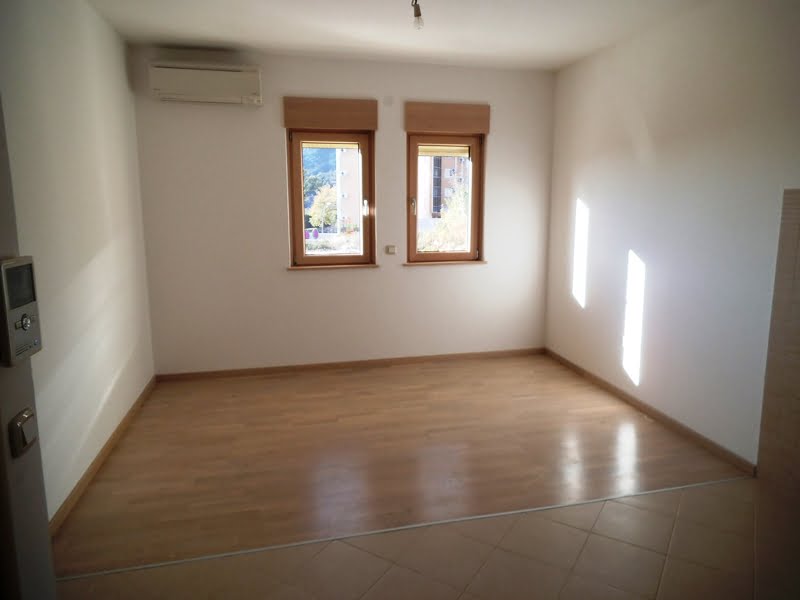 Helles Wohnzimmer mit Laminatboden und Klimaanlage in einer Wohnung in Bečići, Montenegro, Bergblick aus den Fenstern.