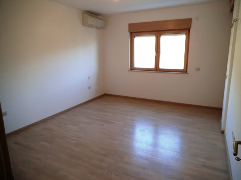 Helles, leeres Schlafzimmer mit Parkettboden und Klimaanlage in einer Wohnung in Bečići, Montenegro.