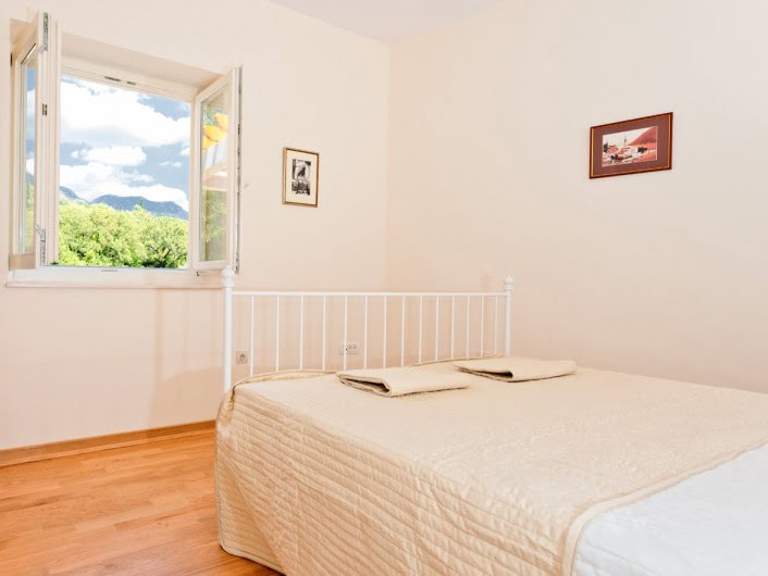 Beyaz yataklı ve dağ manzaralı aydınlık yatak odası, dairede, Herceg Novi şehri, Karadağ.