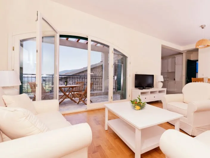 Helles Wohnzimmer mit weißen Möbeln und Zugang zur Terrasse in einer Wohnung in Herceg Novi, Montenegro.