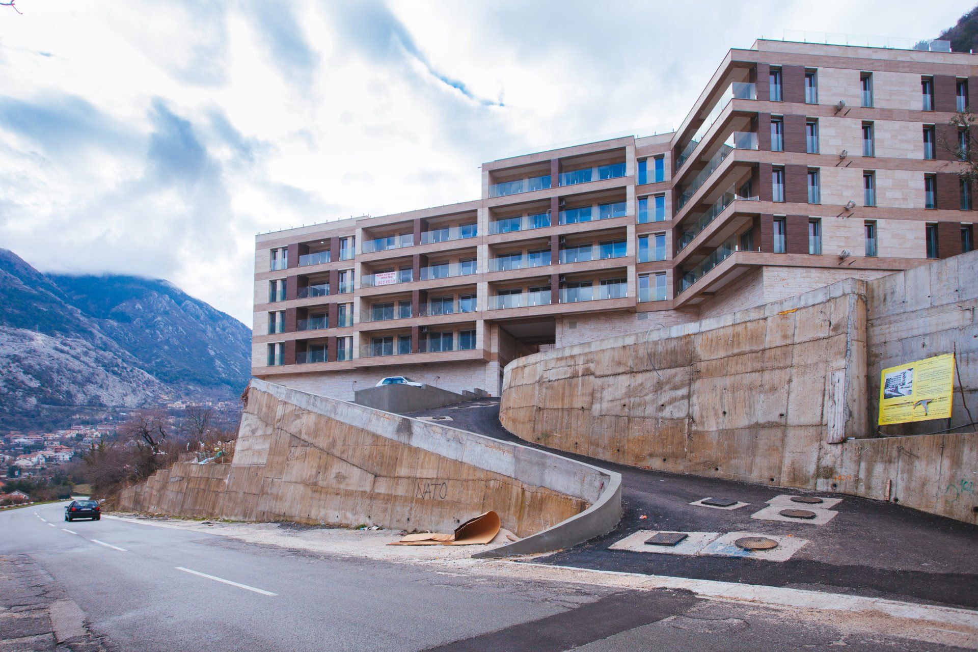 Modern residential complex in Kotor, Montenegro: building facade with panoramic balconies and parking entrance.