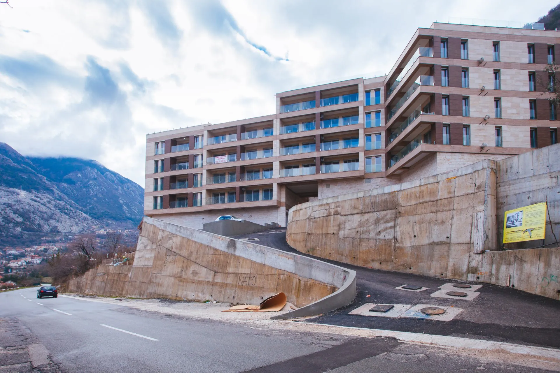 Moderner Wohnkomplex in Kotor, Montenegro: Gebäudefassade mit Panoramabalkonen und Zufahrt zur Parkgarage.