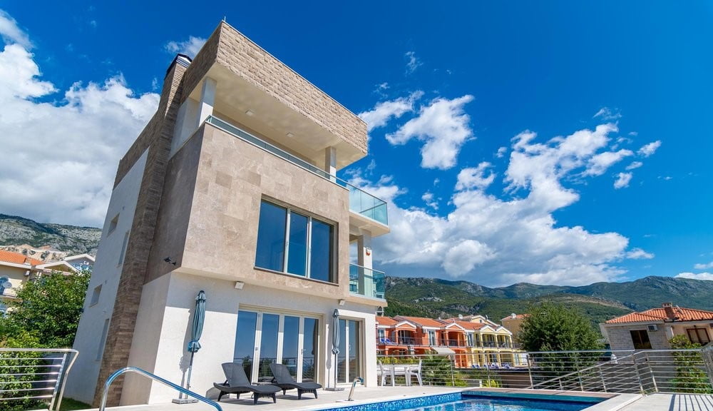 Moderne Villa mit Pool und Terrassen in Bečići, Montenegro: Blick auf die Fassade des Gebäudes und die Berglandschaft.