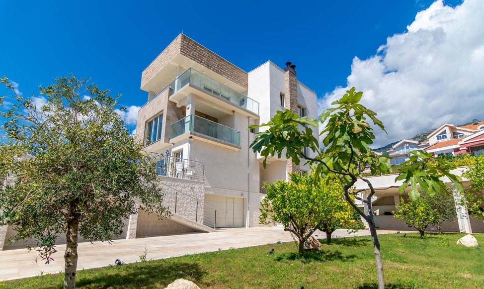 Moderne dreistöckige Villa mit Terrassen und Garten in Bečići, Montenegro: Blick auf die Fassade des Hauses und das umliegende Grundstück.