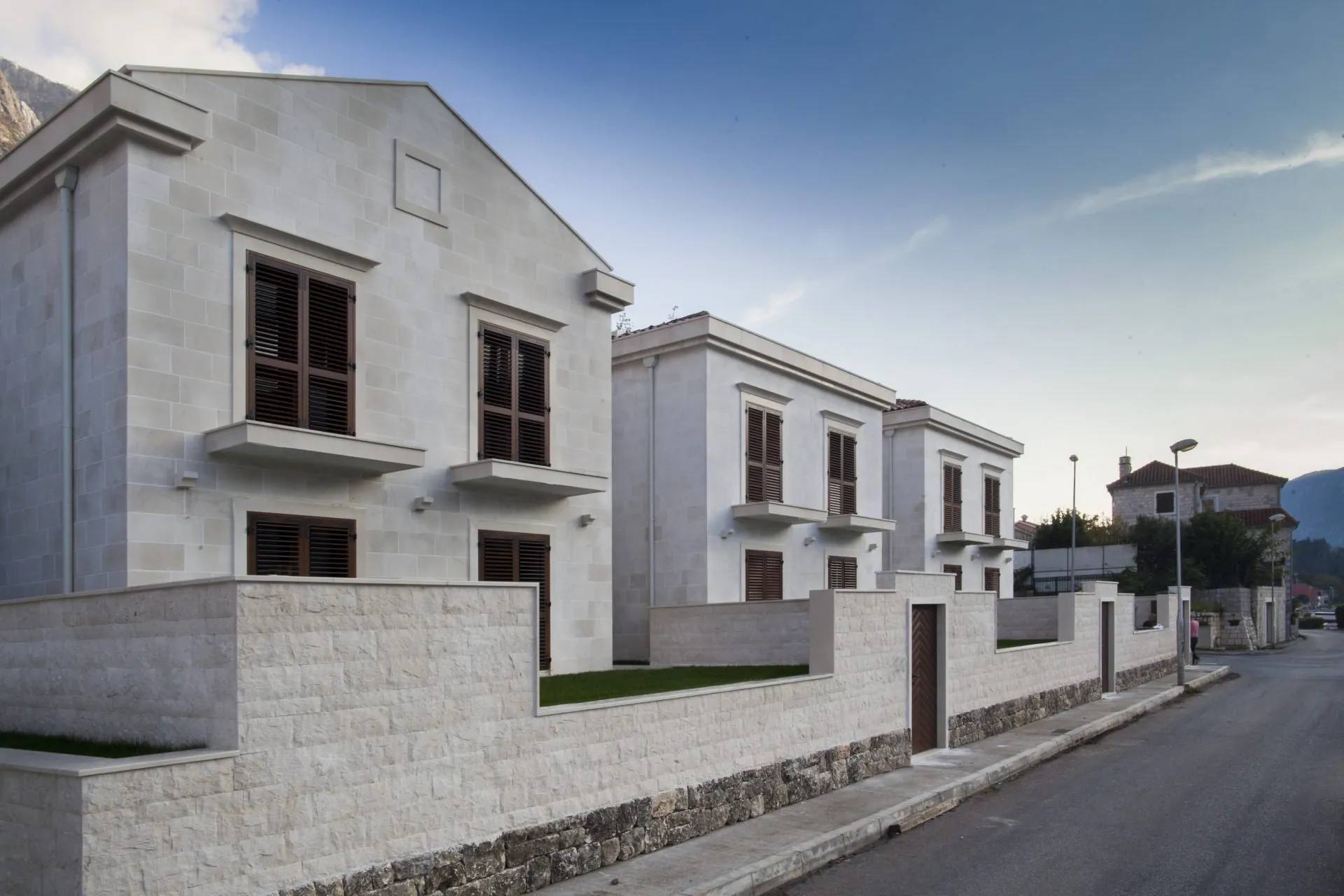 Вид на фасадата на moderne камени куќи со дрвени капаци и ограда од улица.