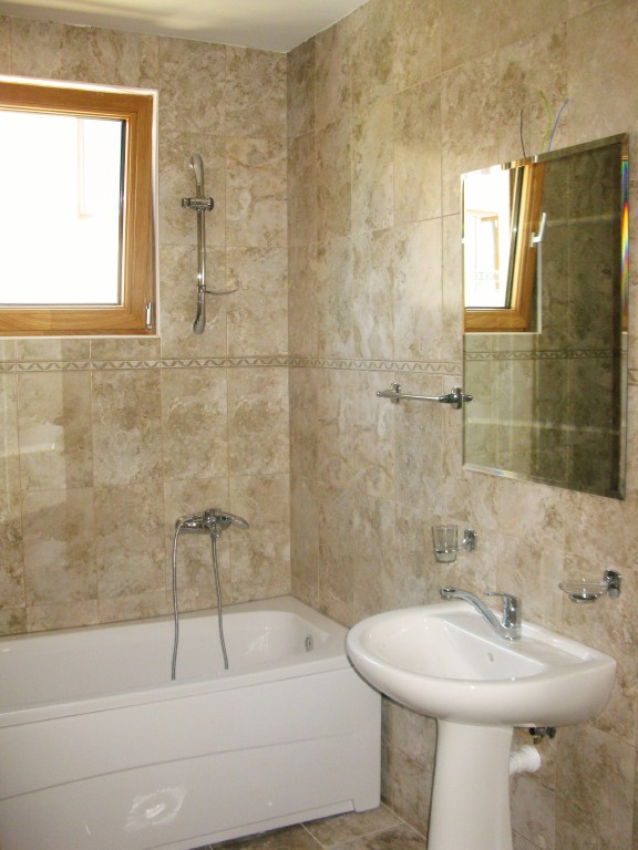 Badezimmer mit weißer Sanitärkeramik und Steinoptik-Fliesenverkleidung in einer Wohnanlage, Igalo, Montenegro.