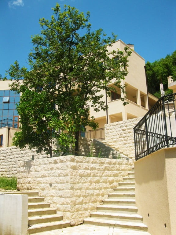 Moderner Wohnkomplex in Igalo, Montenegro: Steintreppe, Terrassen und grüner Baum an der Fassade des Gebäudes.