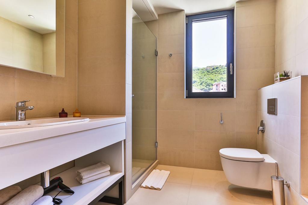 Rafailovići, Karadağ'daki konut kompleksinde dağ manzaralı pencereye sahip, duşakabin ve lavabolu modern banyo.