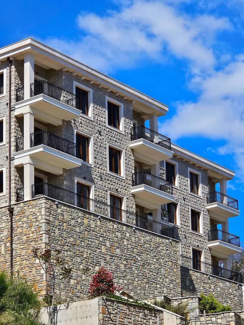 Fassade eines modernen Wohnhauses aus Naturstein mit Balkonen in Budva, Montenegro.