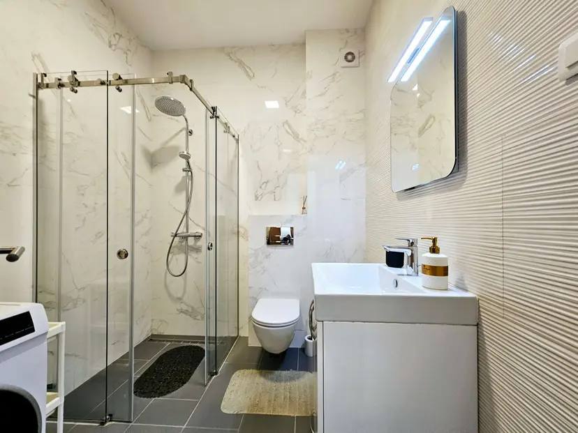 Modernes Badezimmer in einer Wohnung in Budva, Montenegro: Duschkabine, Sanitäranlagen und Marmoroptik.