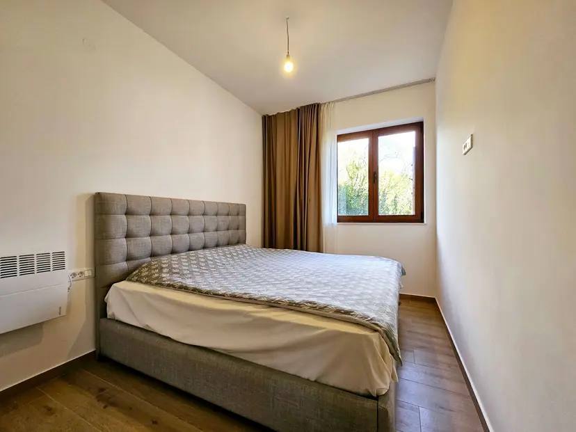 Gemütliches Schlafzimmer mit Doppelbett in einer Wohnung in Budva, Montenegro: helles Interieur, Parkett und Blick aus dem Fenster.