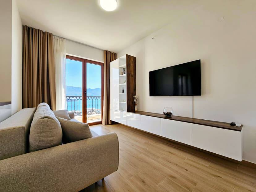 Wohnzimmer in einer modernen Wohnung in Budva, Montenegro: Sofa, TV-Bereich und Balkon mit Panoramablick auf das Meer.