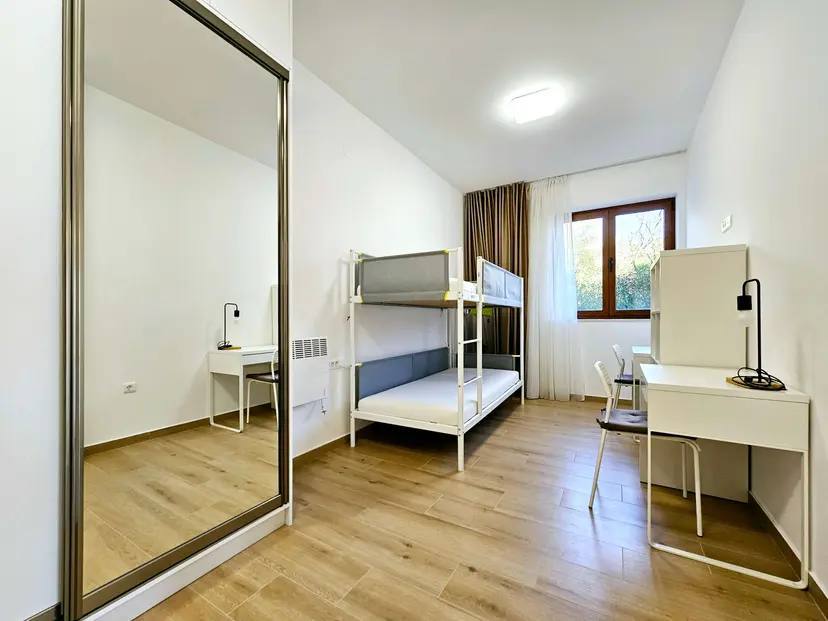 Schlafzimmer mit Etagenbett und Schreibtischen in einer Wohnung, Budva, Montenegro: modernes Interieur mit Spiegel.