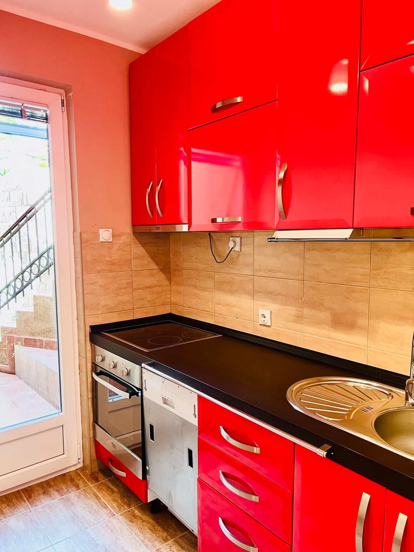 Cuisine lumineuse avec façades rouges brillantes dans un appartement à Petrovac, Monténégro, avec accès à la terrasse et électroménager intégré