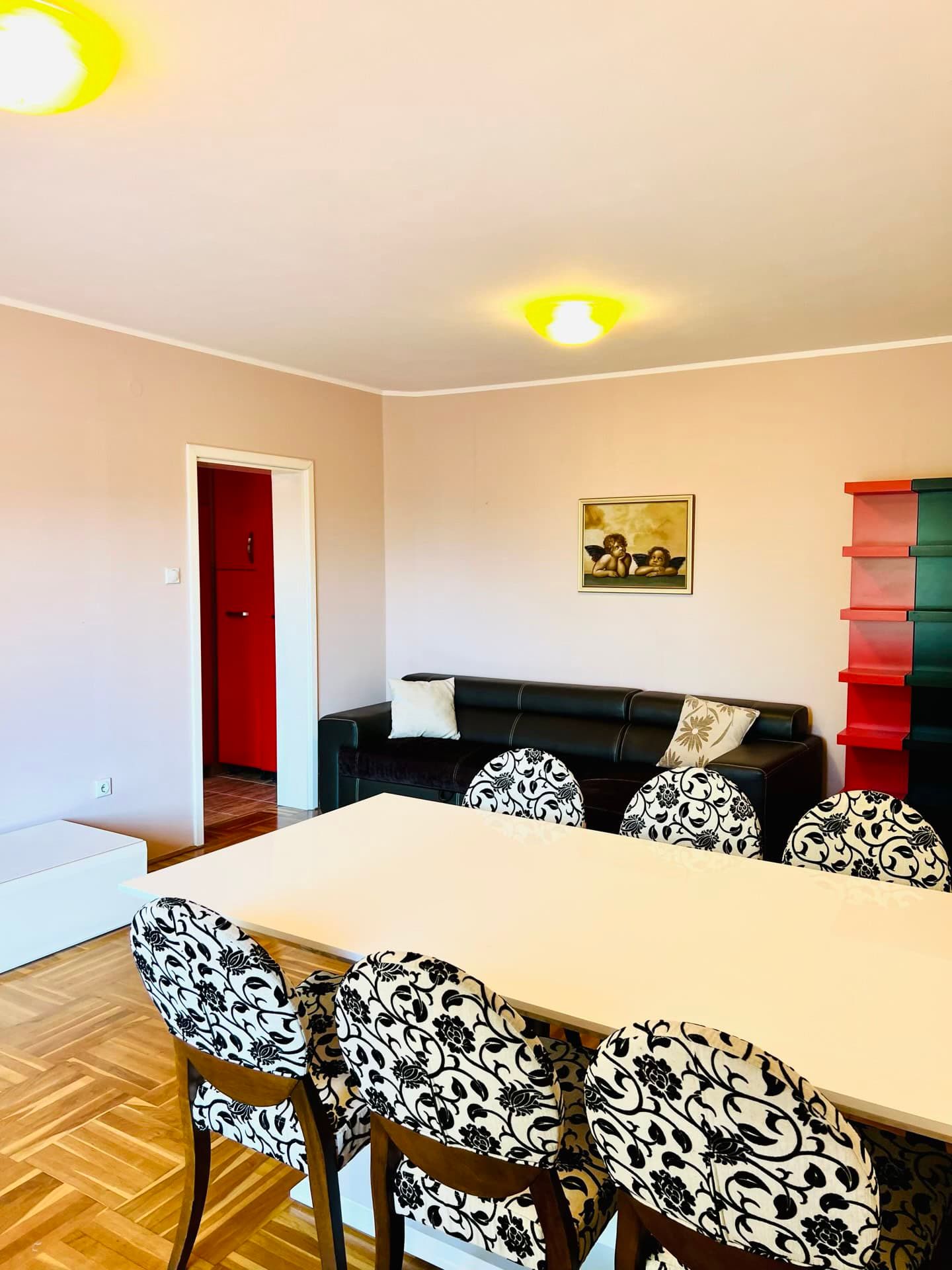 Salon avec coin repas dans un appartement à Petrovac, Monténégro : canapé noir, table et chaises avec revêtement à motifs.