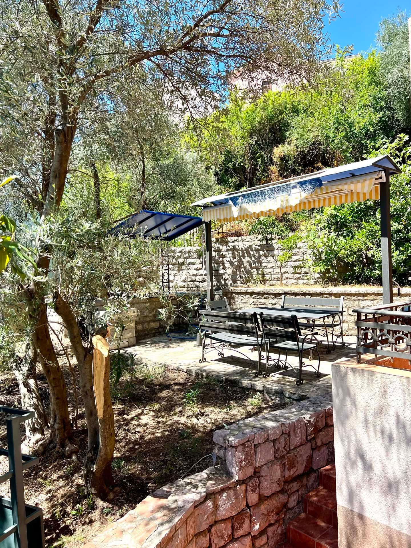 Terrasse confortable avec mobilier de jardin et auvent dans le jardin privé de l’appartement à Petrovac, Monténégro.