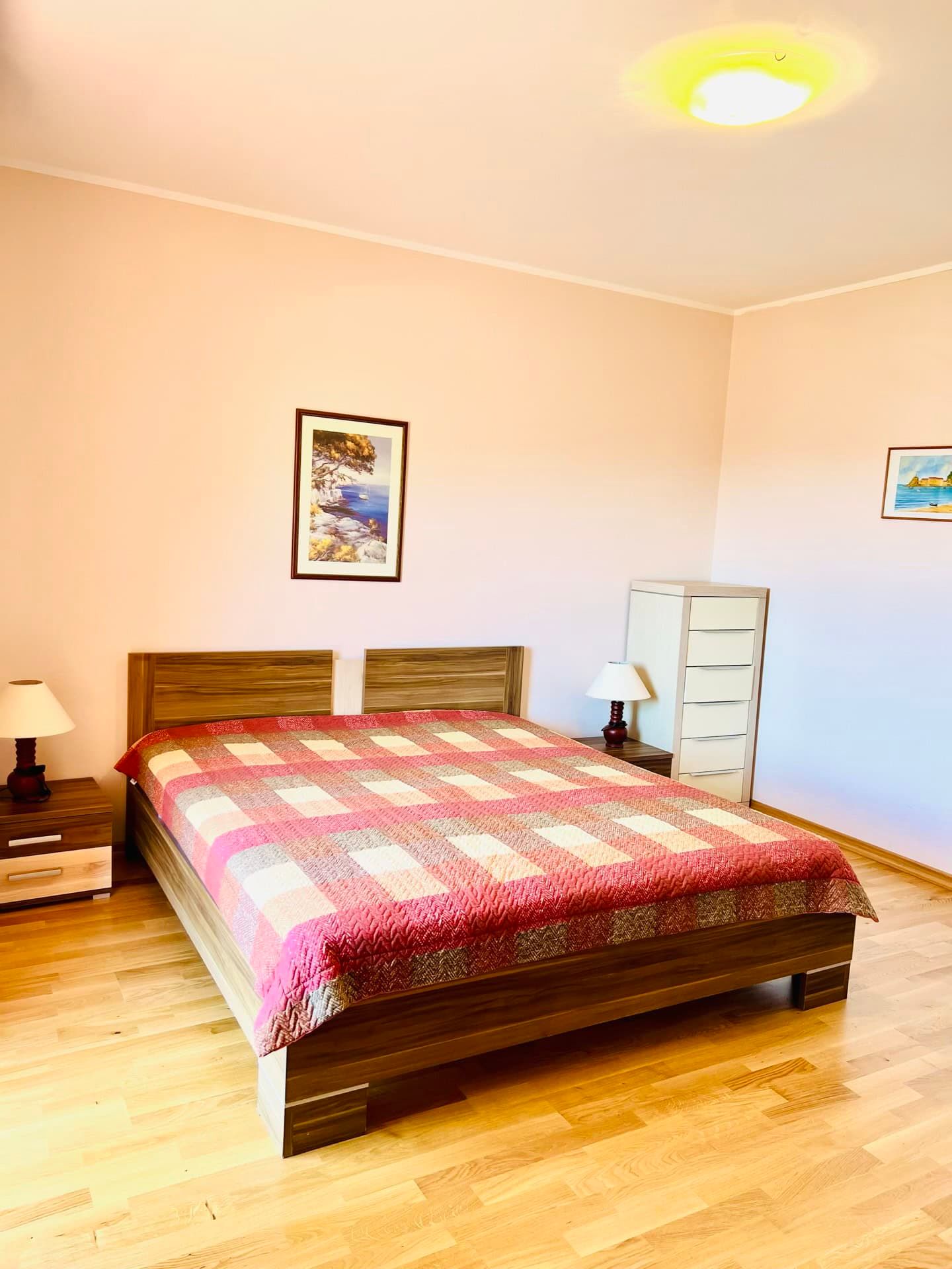 Chambre lumineuse avec lit double et parquet dans un appartement à Petrovac, Monténégro.