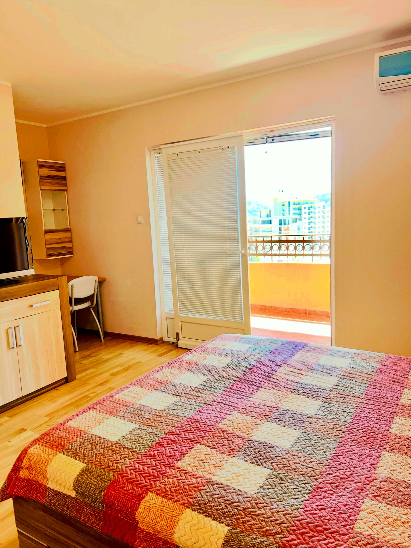 Chambre dans un appartement à Petrovac, Monténégro : lit double, mobilier clair, accès au balcon avec vue sur la ville.