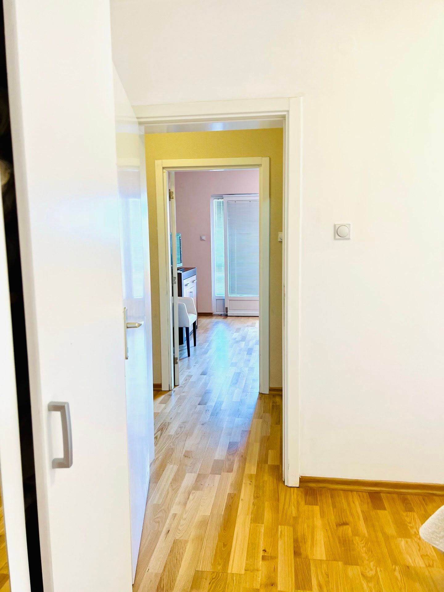 Vue depuis la chambre sur un salon lumineux avec parquet et accès au balcon dans un appartement, ville de Petrovac, Monténégro.