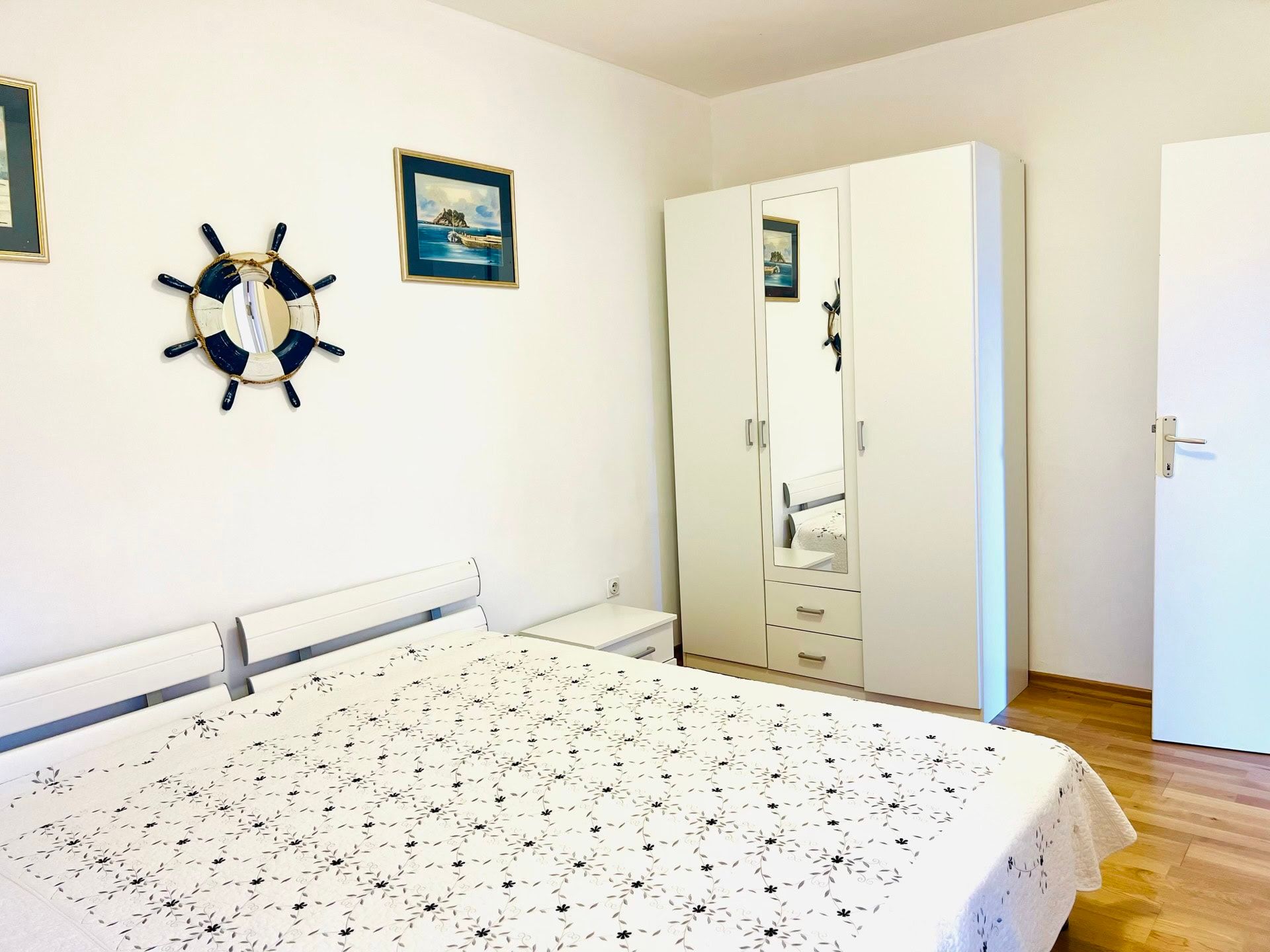 Chambre lumineuse avec mobilier blanc et décoration marine dans un appartement à Petrovac, Monténégro.