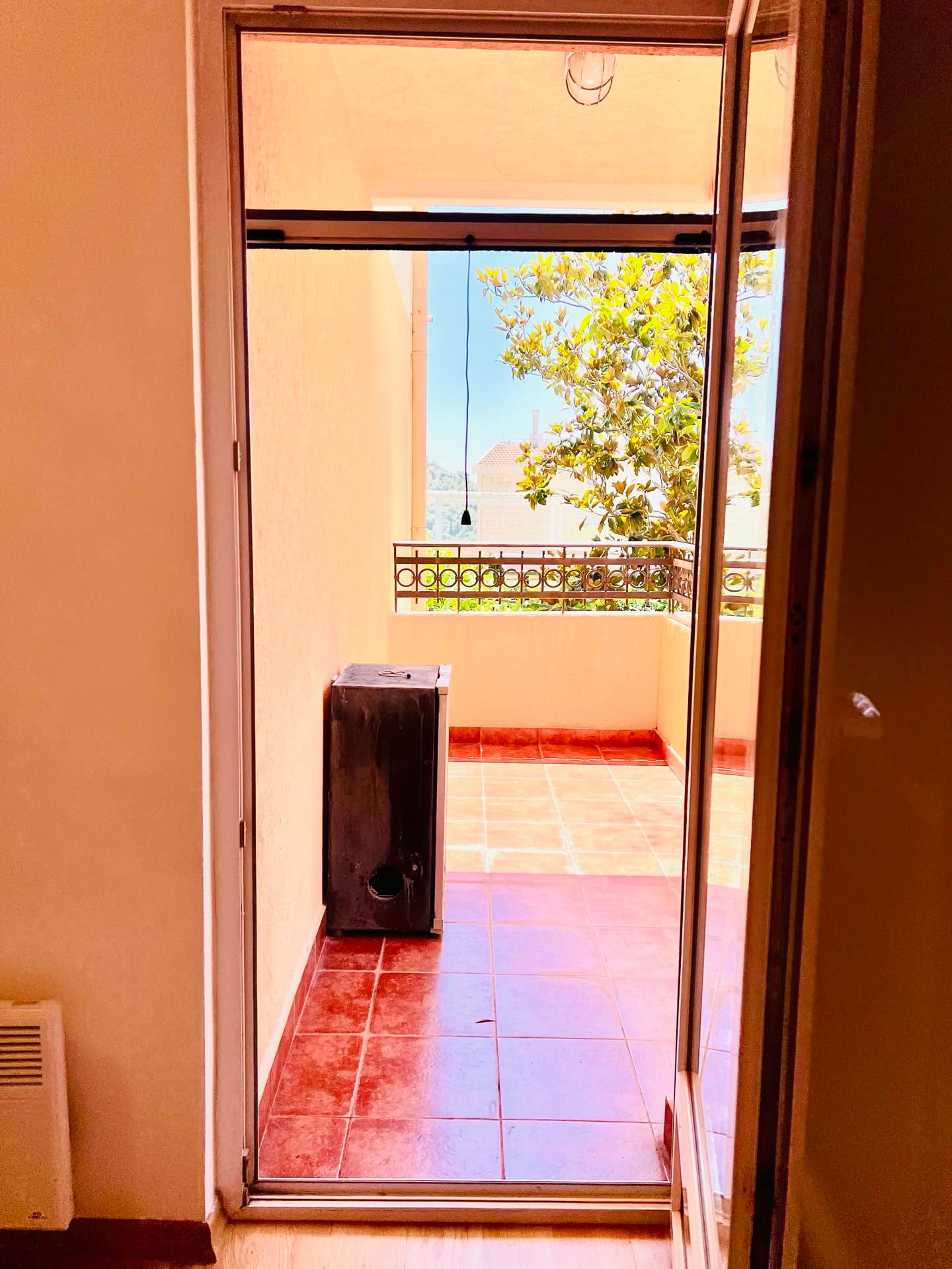 Vue depuis la chambre sur le balcon ouvert avec carrelage en terre cuite dans un appartement à Petrovac, Monténégro.