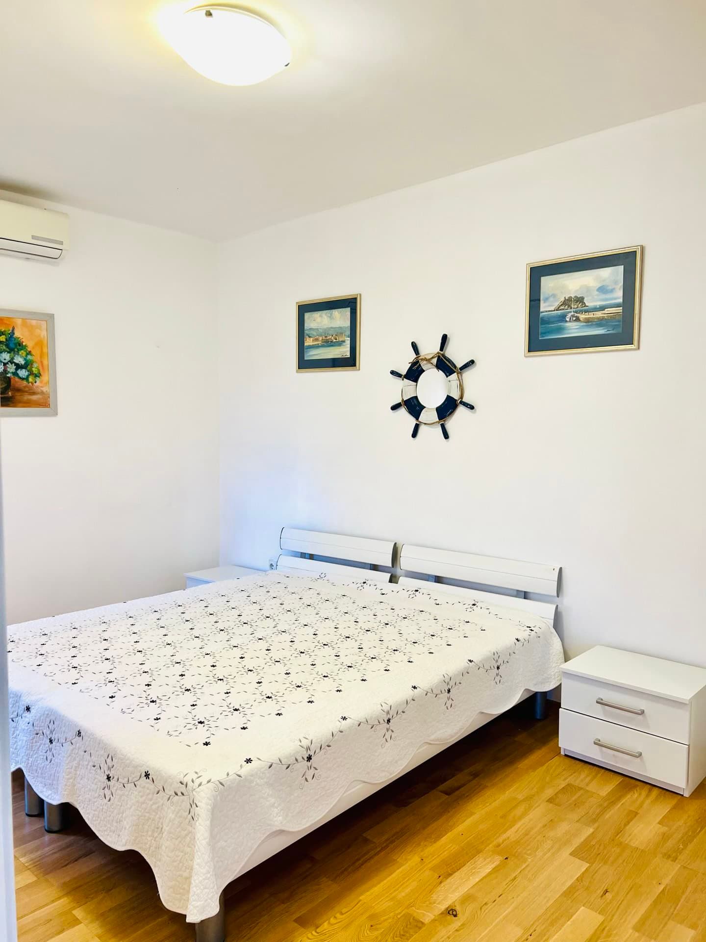 Chambre lumineuse avec lit double dans un appartement à Petrovac, Monténégro : décoration marine et parquet.