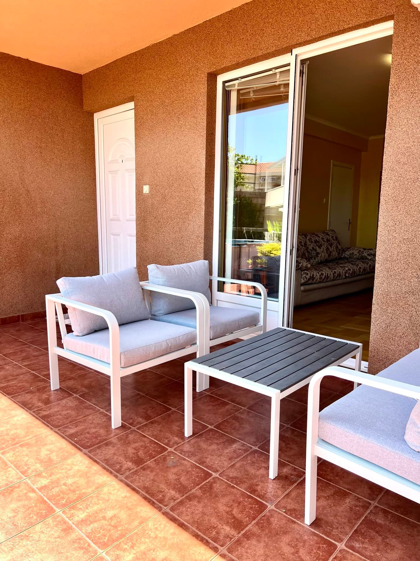 Terrasse confortable avec mobilier de jardin dans un appartement à Petrovac, Monténégro : vue sur le balcon donnant sur le salon.