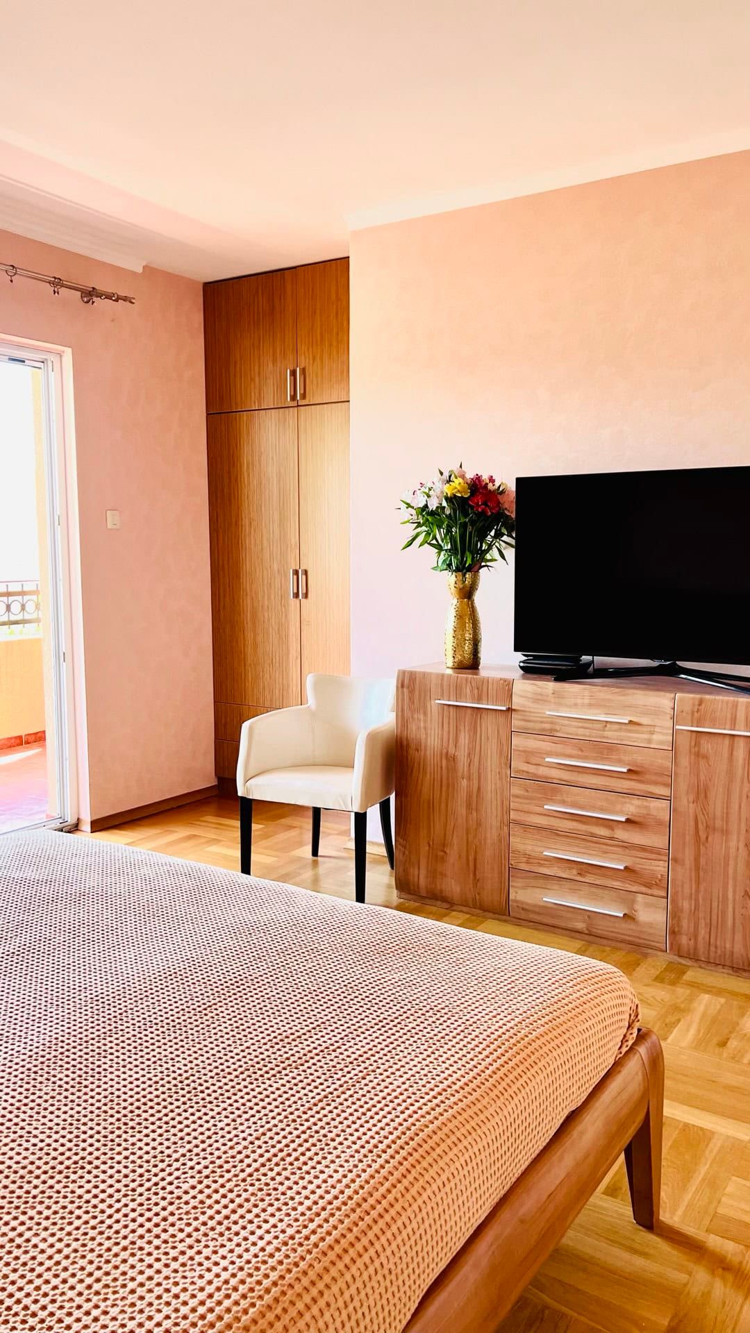 Chambre cosy avec mobilier en bois, parquet et accès au balcon dans un appartement à Petrovac, Monténégro.