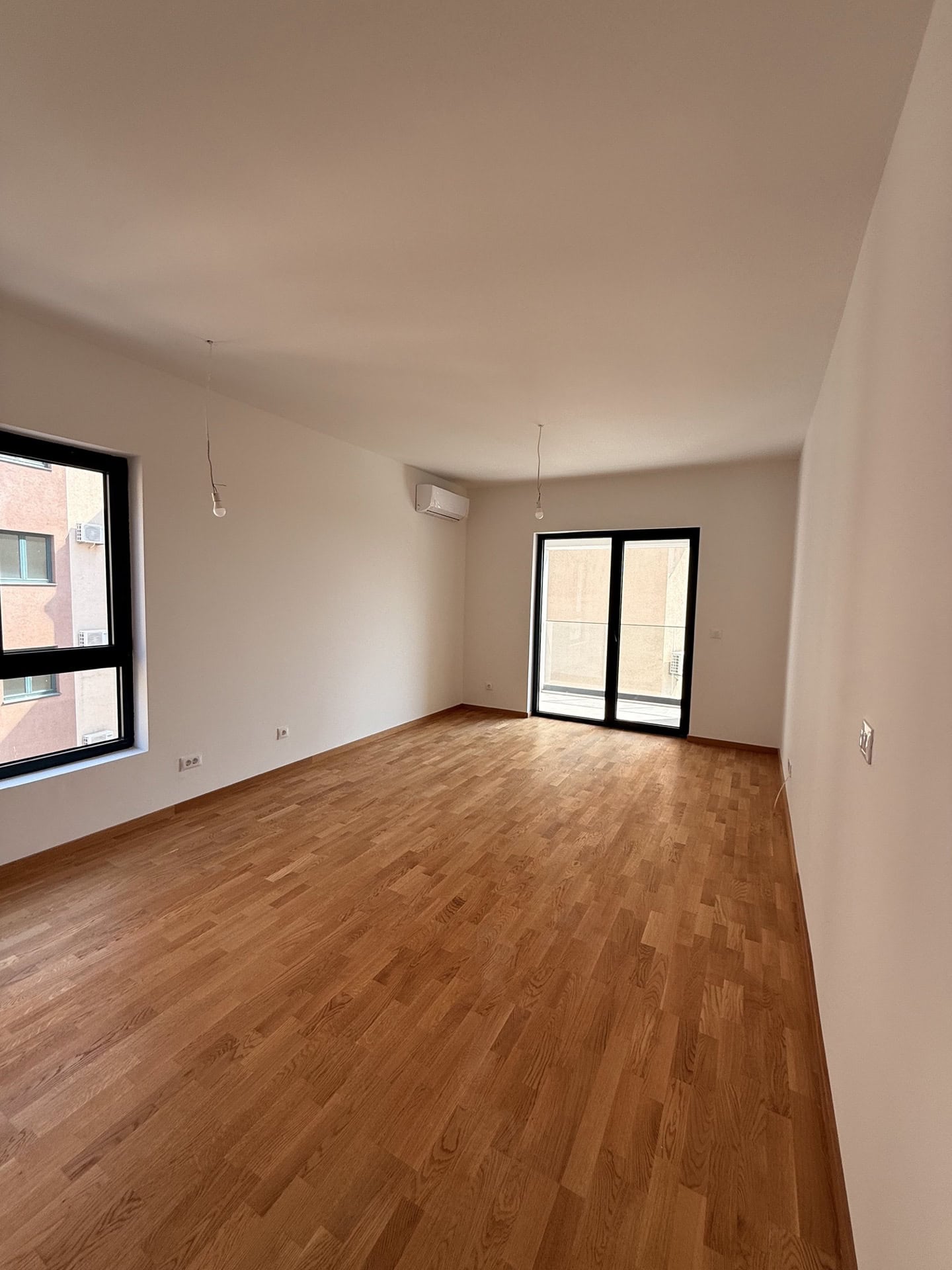 Helles Wohnzimmer mit Parkett und Zugang zum Balkon in einer neuen Wohnung, Bečići, Montenegro.