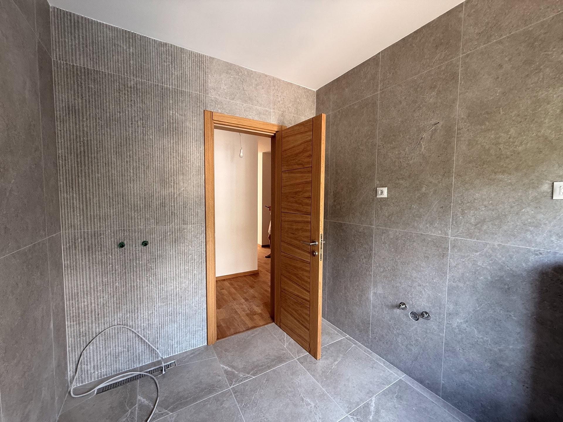 Modernes Badezimmer mit grauen Fliesen in einer neuen Wohnung in Bečići, Montenegro.