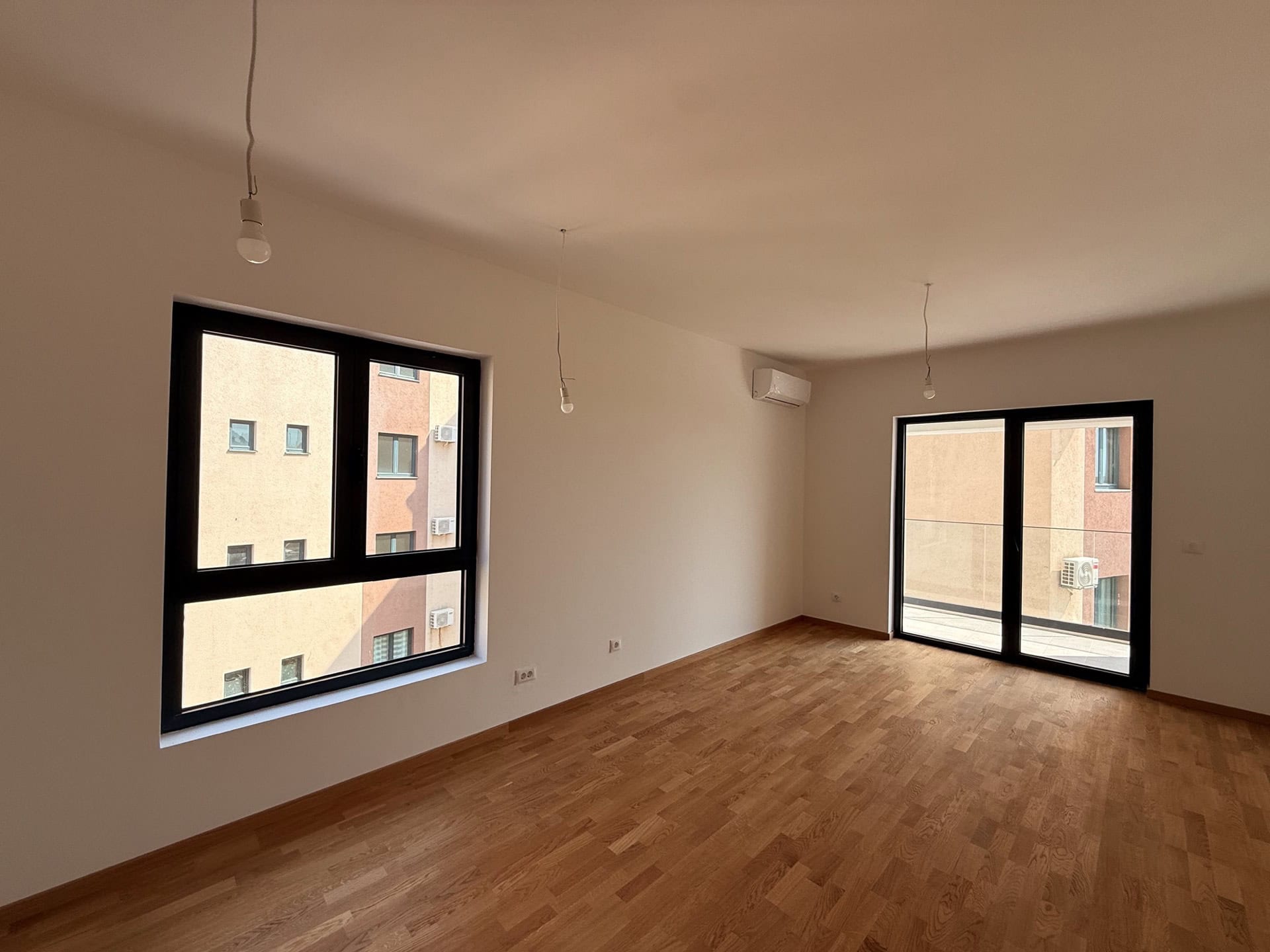 Helles Wohnzimmer mit Parkett und Panoramafenstern in einer neuen Wohnung, Bečići, Montenegro.