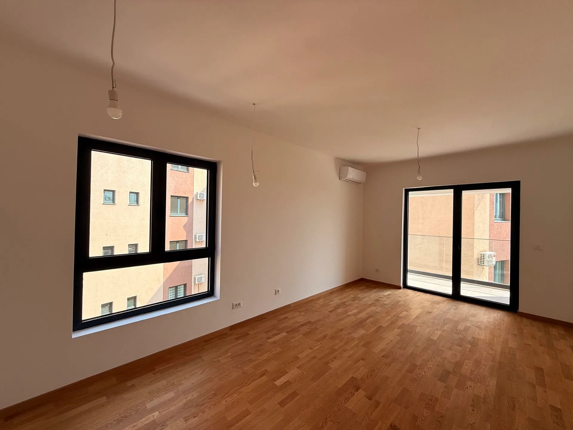 Leeres Zimmer mit Holzboden und großen Fenstern