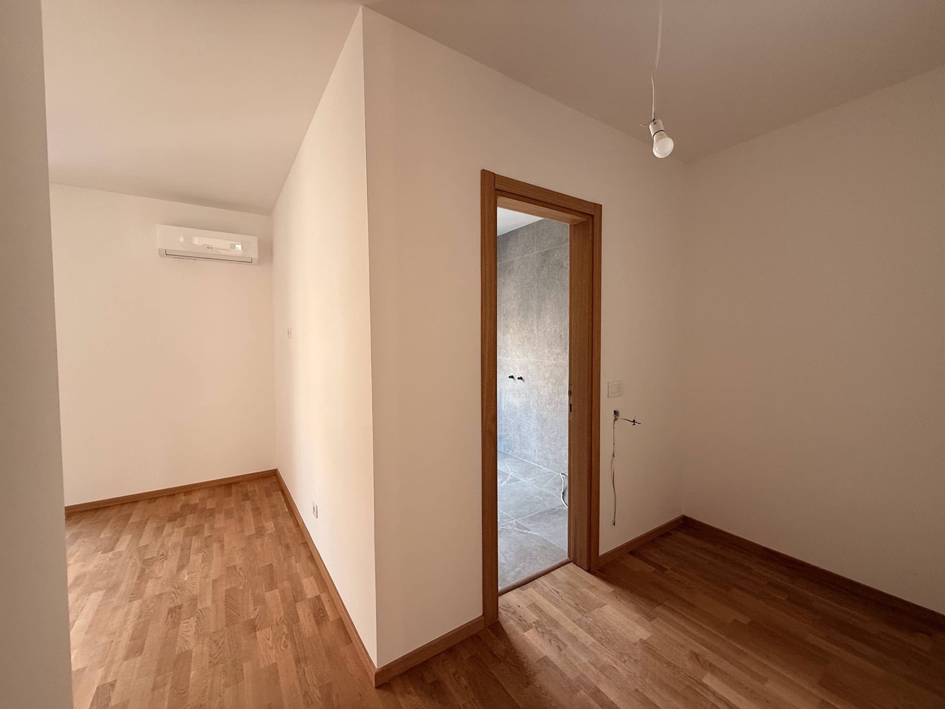 Helles Wohnzimmer mit Parkett und Klimaanlage in der Wohnung, Bečići, Montenegro, Blick auf die Badezimmerausstattung.
