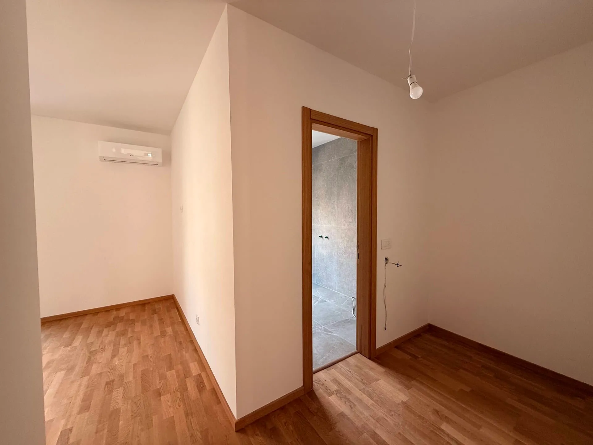 Leeres Zimmer mit Holzboden und einem Türdurchgang.