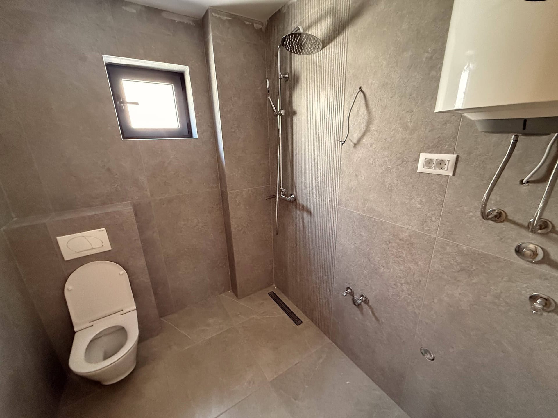 Modernes Badezimmer in einer Wohnung in Bečići, Montenegro: Duschkabine, Vorwandinstallation und graue Fliesen.