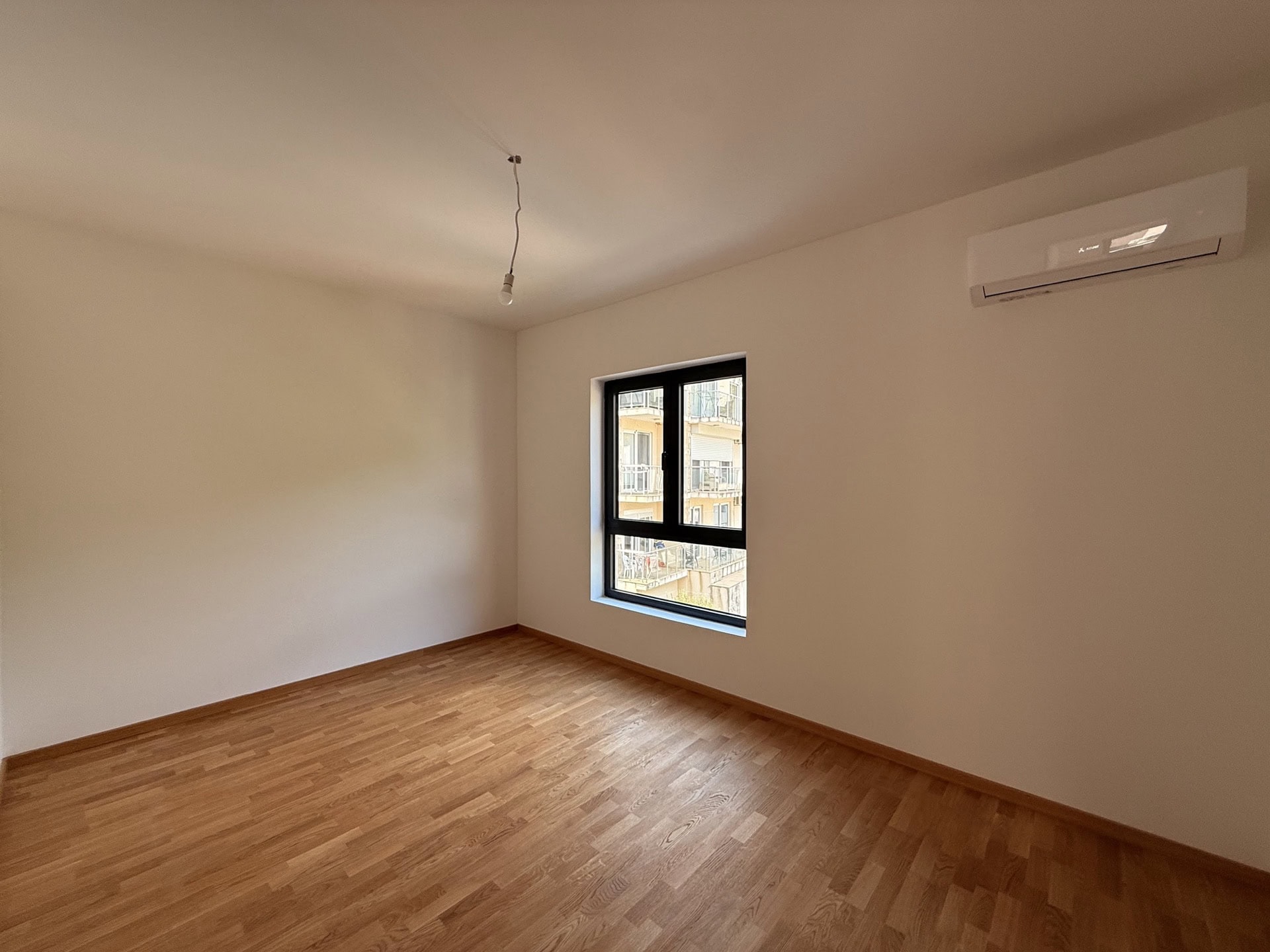 Helles Schlafzimmer mit Parkett und Klimaanlage in einer Wohnung zum Verkauf in Bečići, Montenegro.