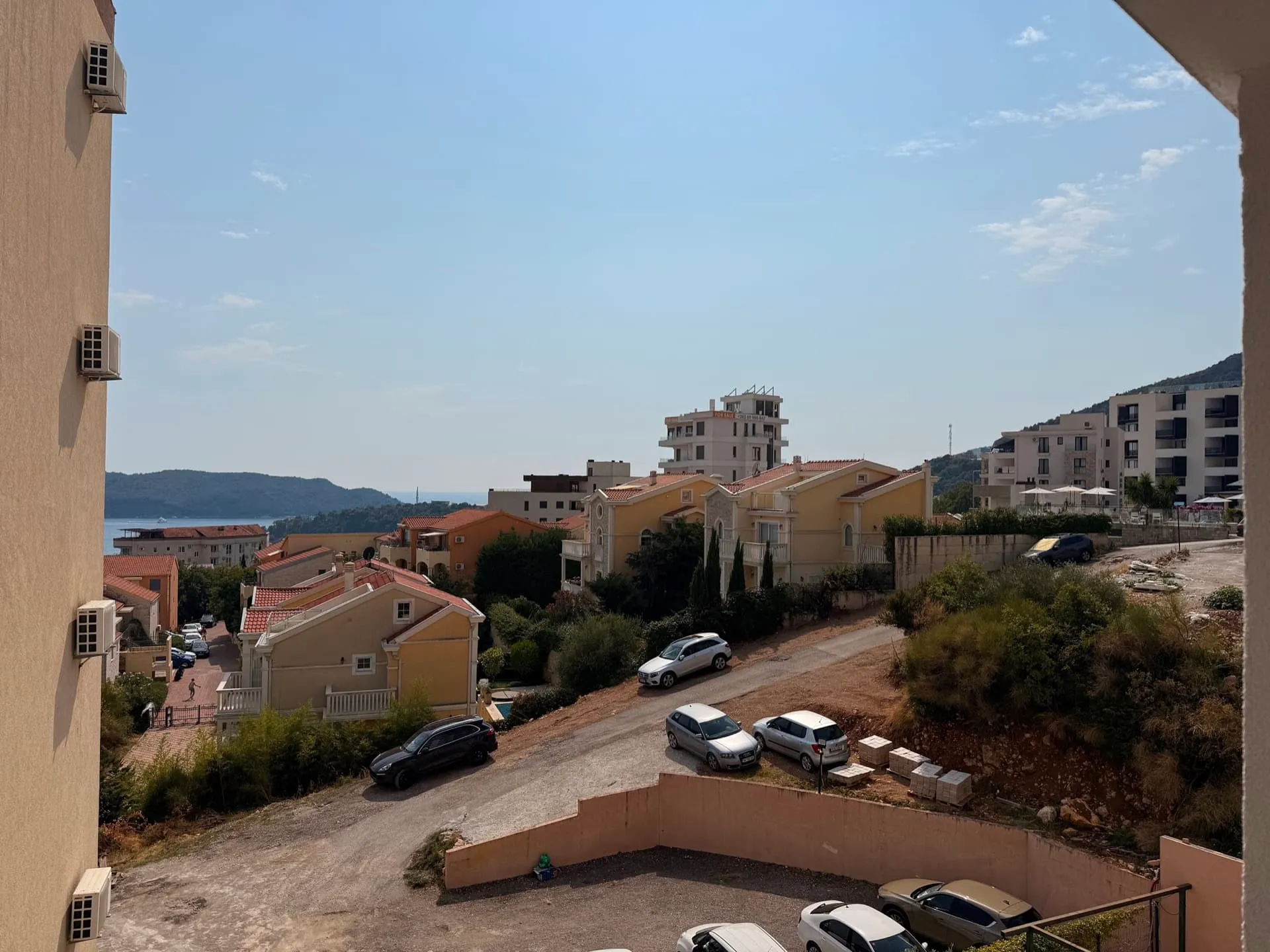 Balkonblick auf eine Küstenstadt, Hügel und geparkte Autos