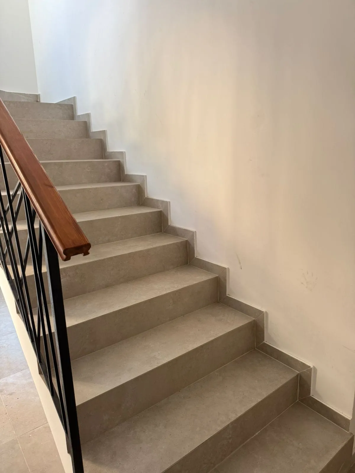 Staircase with beige tiles and wrought-iron railings in a modern apartment, Tivat, Montenegro.