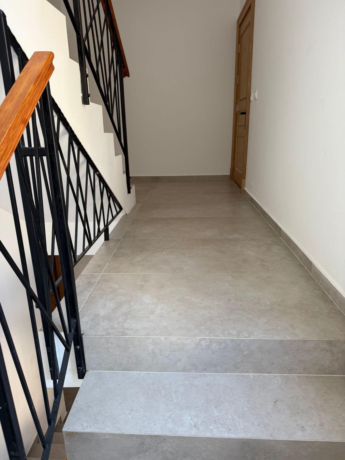 Treppe mit schmiedeeisernem Geländer und Holzhandläufen in einer modernen Wohnung, Stadt Tivat, Montenegro.