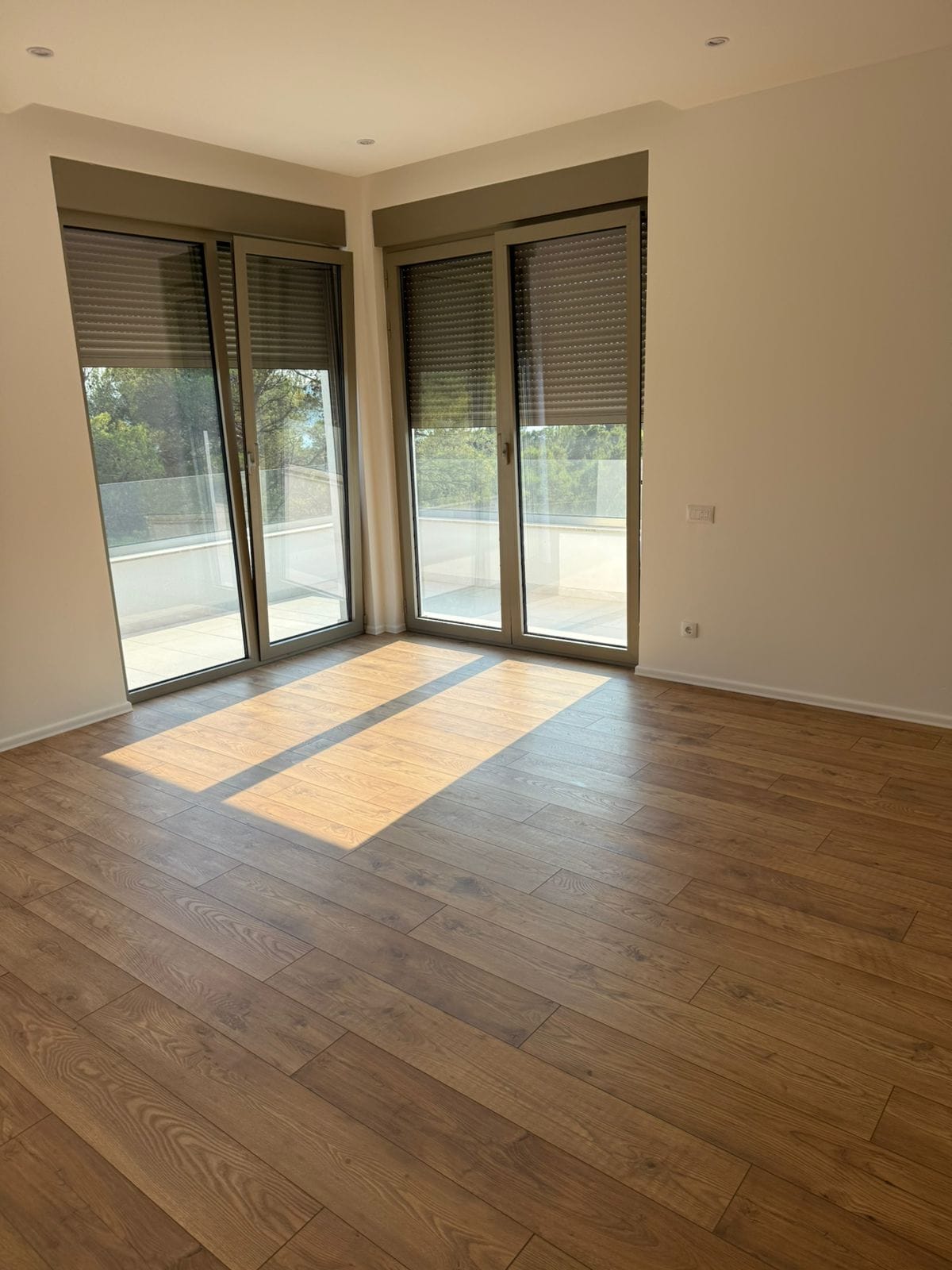 Helles Wohnzimmer in einer Wohnung in Tivat, Montenegro: Panoramafenster, Zugang zur Terrasse und hochwertiges Laminat.
