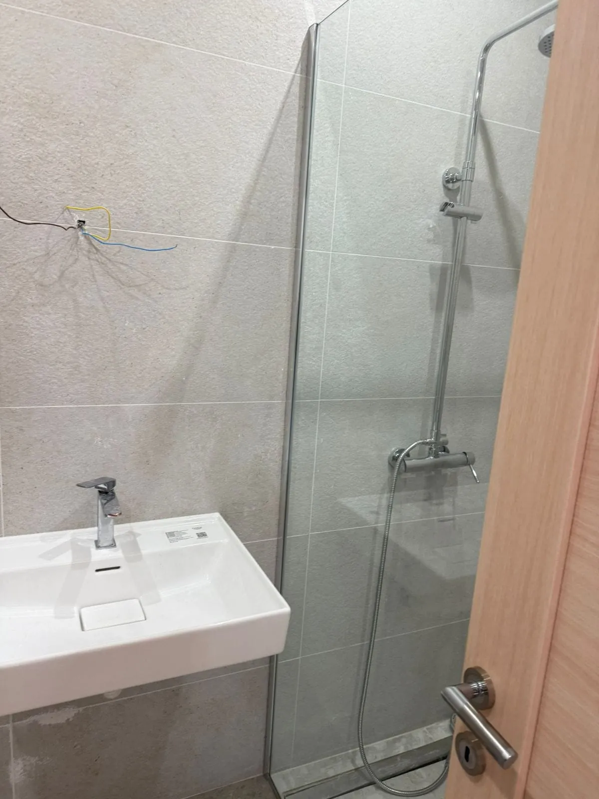 Modern bathroom in an apartment in Tivat, Montenegro: shower cabin, white sink, and tiled finish.