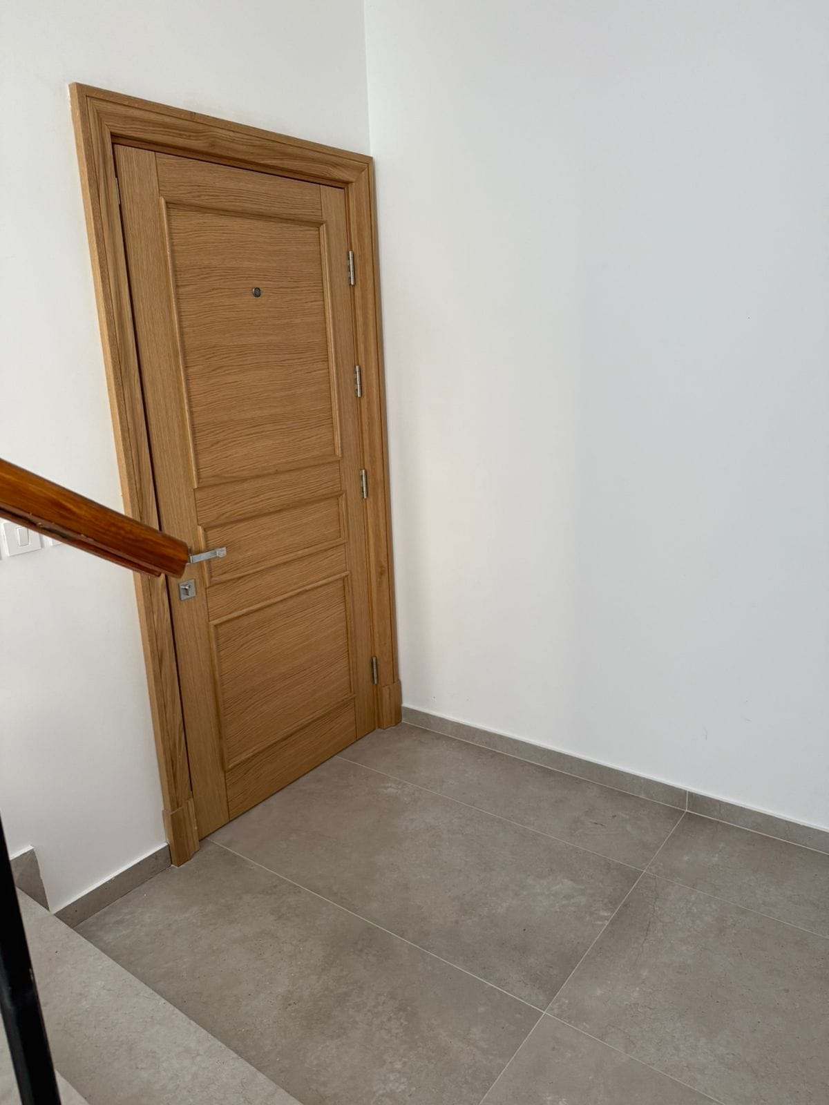 Innentür aus hellem Holz im Interieur einer Wohnung in Tivat, Montenegro, mit Bodenbelag aus Feinsteinzeug.